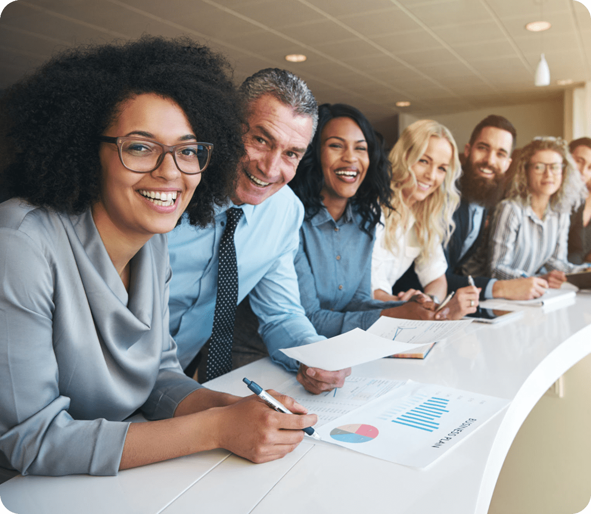 Diverse group smiling in an office meeting.